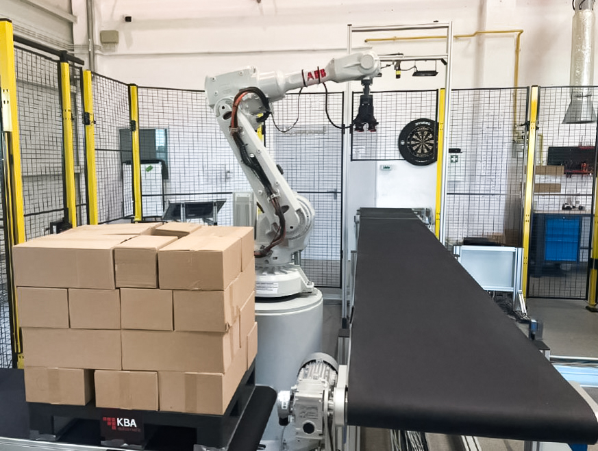 Fizyczna realizacja naszego rozwiązania z wykorzystaniem robota ABB – zdjęcie przedstawia stanowisko testowe z robotem przemysłowym podczas paletyzacji